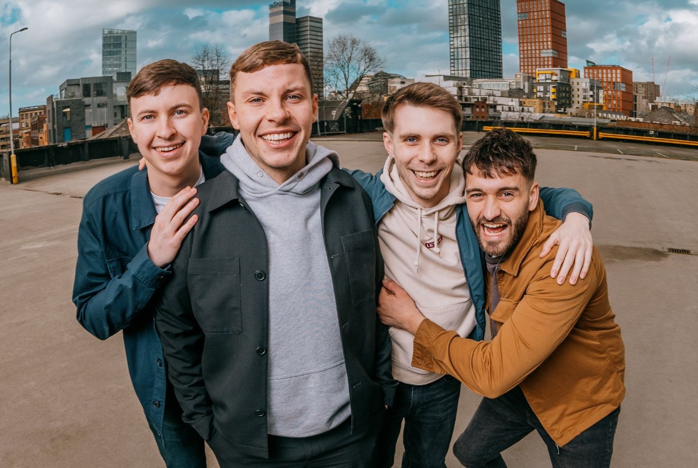 Four members of The Lilacs stood in an empty car park with high rise flats in the background
